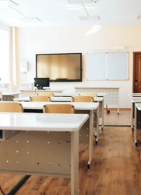 Aula moderna con pupitres, pizarra digital y proyector, usada para formación en logística y ADR.