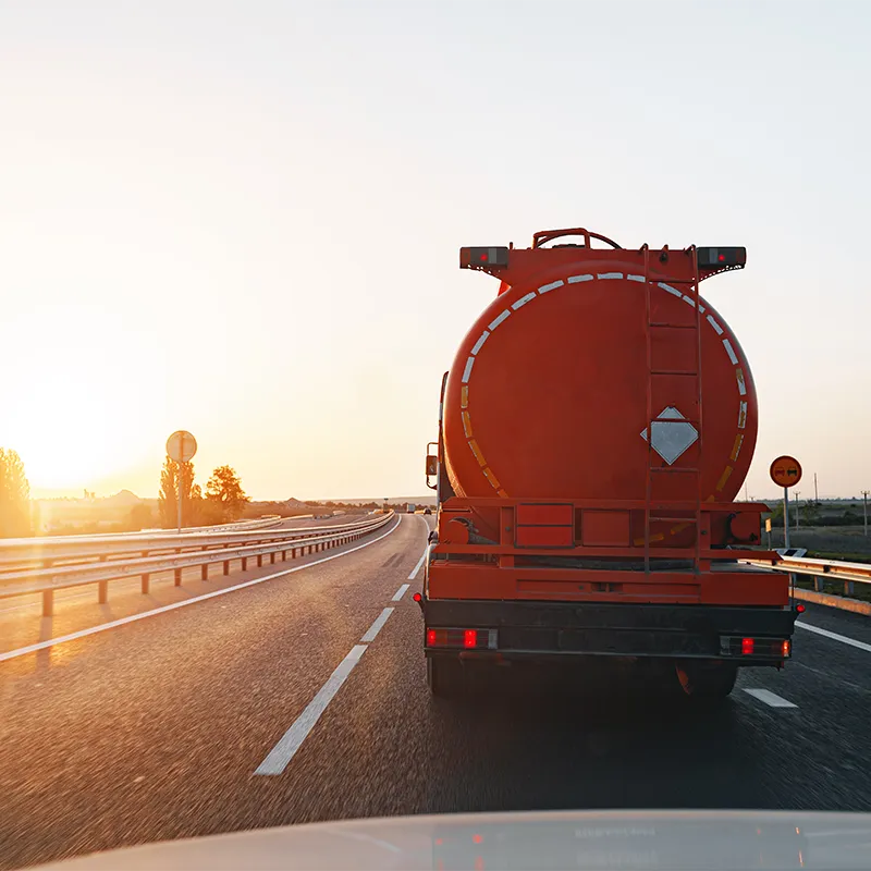 Camión cisterna transportando mercancías peligrosas por carretera, cumpliendo normativa ADR al amanecer.